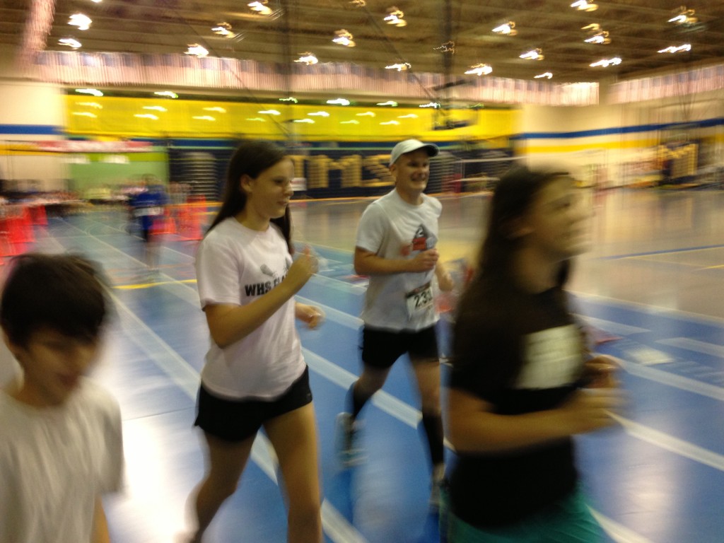 Centreville's Eric Setash runs his bell lap of the Grant Pierce Indoor 50k flanked by his children. Photo: Charlie Ban