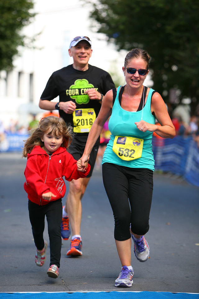 Selina Read gets some last-minute company across the Parks Half Marathon finish line, while Rob Kennedy thanks his lucky stars the newcomer isn't in his age group. Photo: Dan Reichmann, MCRRC