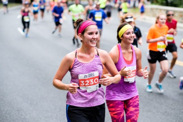 Christina Wryter and Lindsey Bernal grin their way down Rock Creek Parkway at the Navy-Air Force Half Marathon. Photo: Dustin Whitlow/DWhit Photography