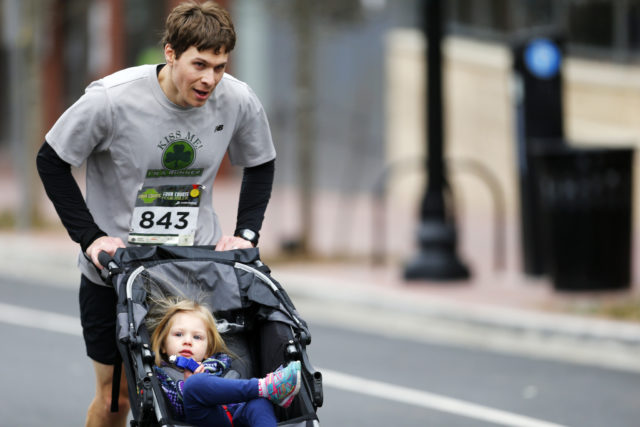 Adam Schwaber pushes his daughter Julia up Wilson Boulevard at the end of the Four Courts Four Miler. 