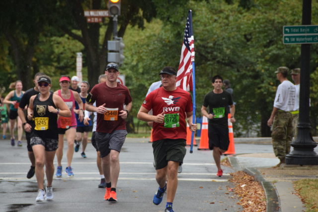 Brian Butler, of York, Pa., carries the flag in the sixth mile of the Army Ten-Miler. Photo: Charlie Ban